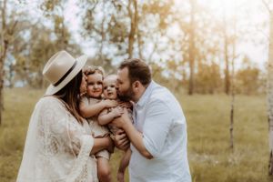 Family embraces in tender moment during golden hour outdoor photo session.