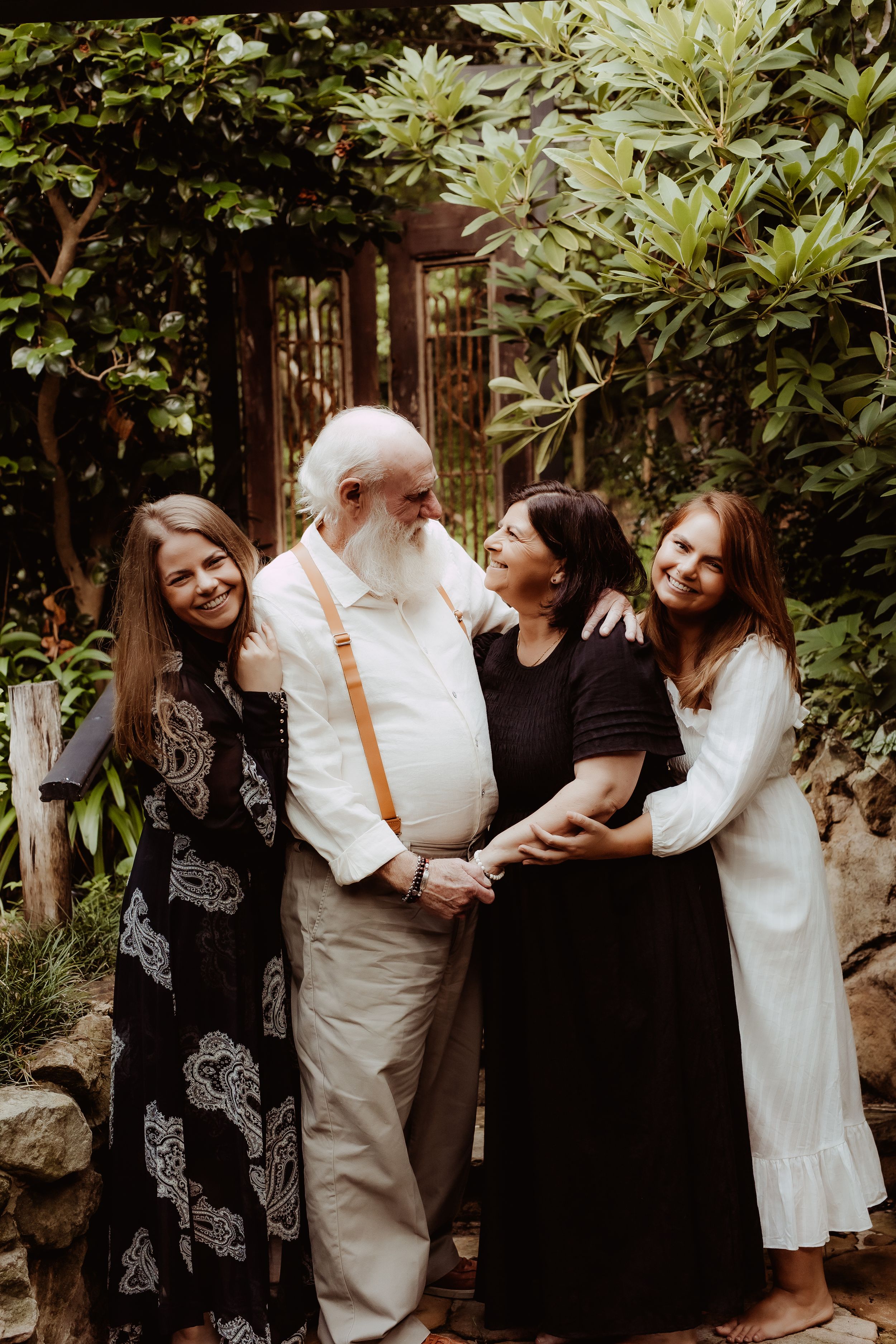 A group shares laughter and embraces in a lush garden setting during a wedding celebration.