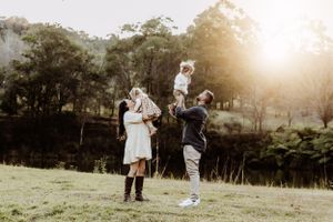 Family enjoying outdoor activities in a grassy field during golden hour.