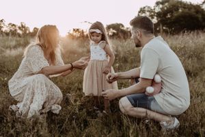 A family plays together in a grassy field at sunset creating joyful moments.