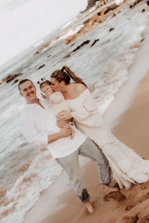 Romantic couple playing and dancing together on a sandy beach near ocean waves.