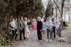 Large family group photo with multiple generations lined up in front of trees.