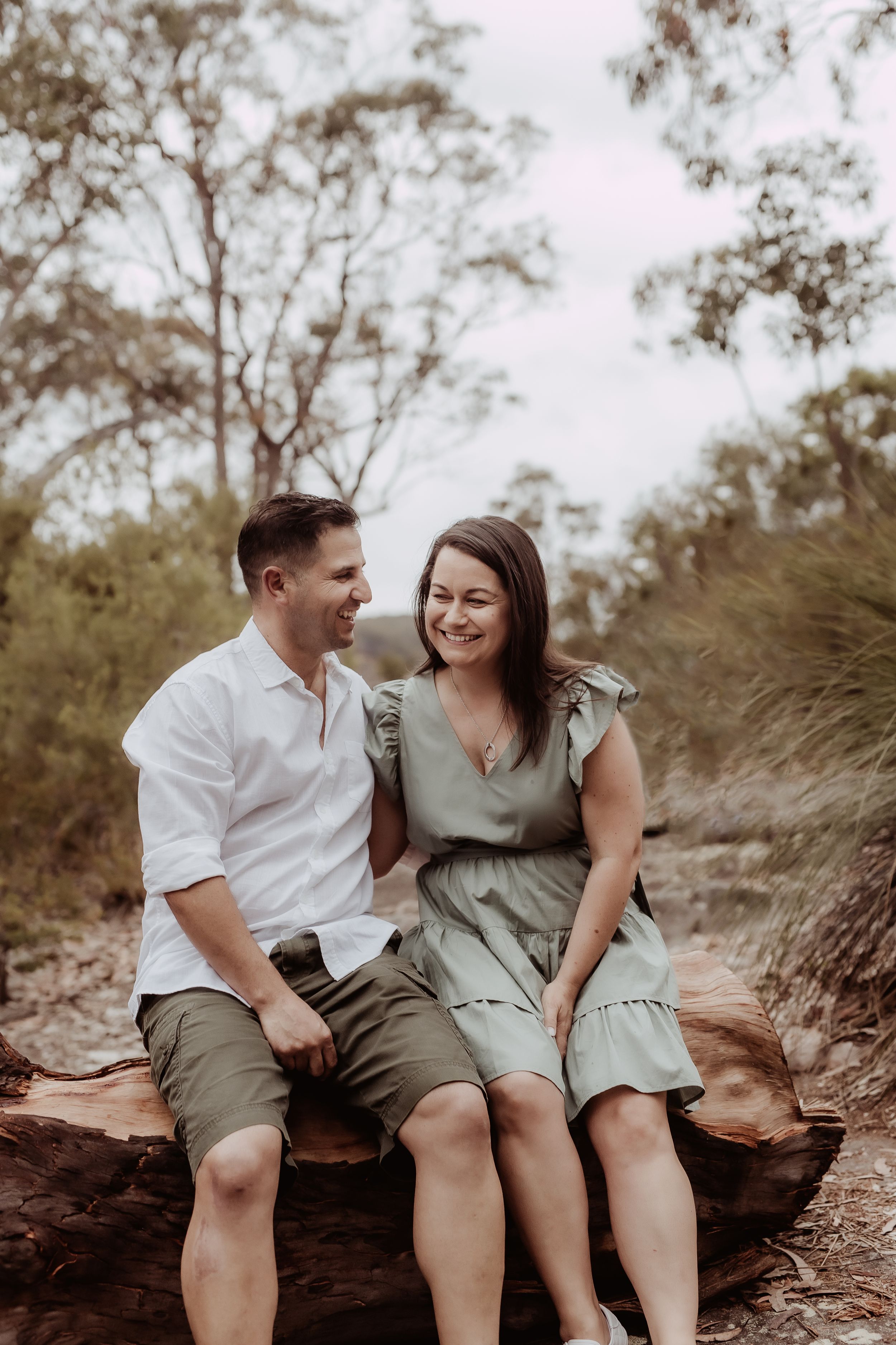 Couple shares intimate moment while sitting on rocks in outdoor setting.