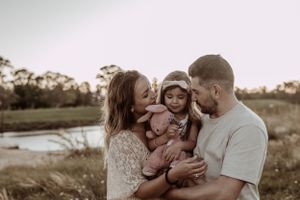Family members share an intimate moment together in a natural outdoor setting.