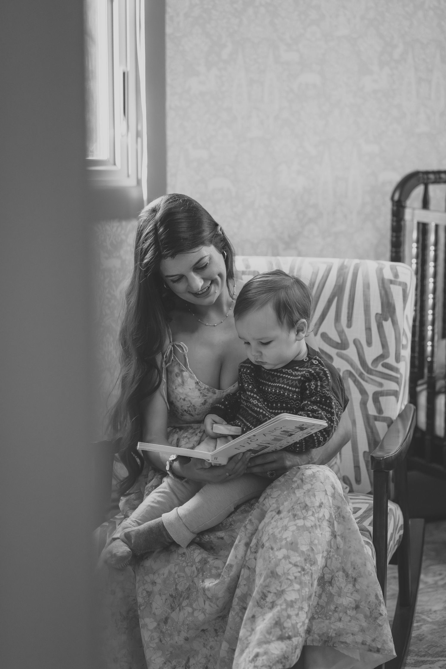 Mother and young child share a tender moment reading a book together in black and white.
