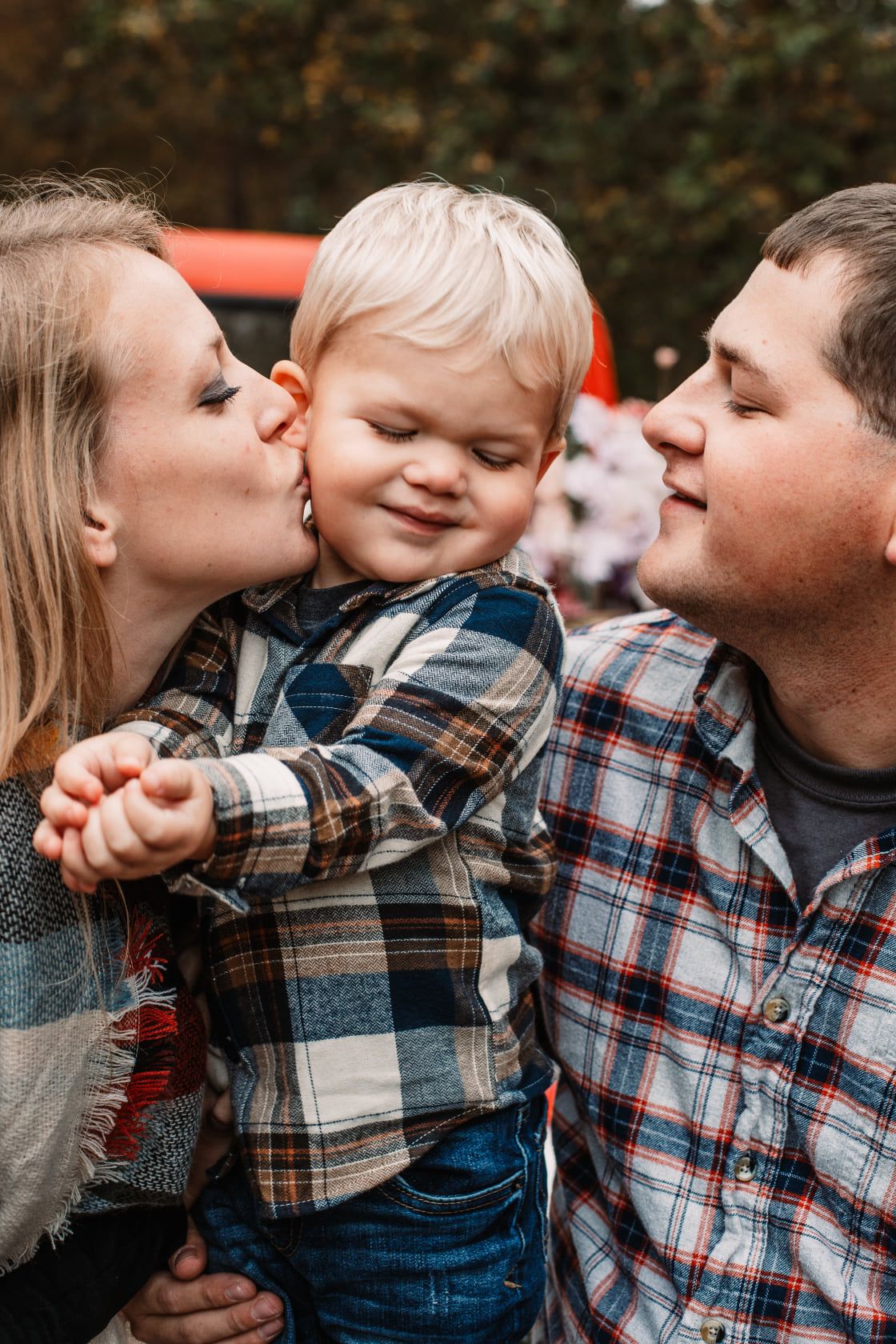 Candid family moment showing affectionate kisses in plaid shirts.
