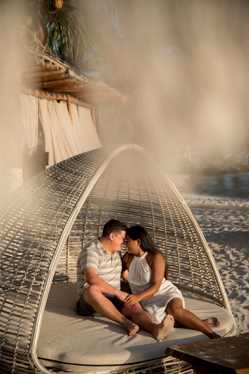 The couple sharing a romantic face-to-face moment, surrounded by the scenery of the beach club