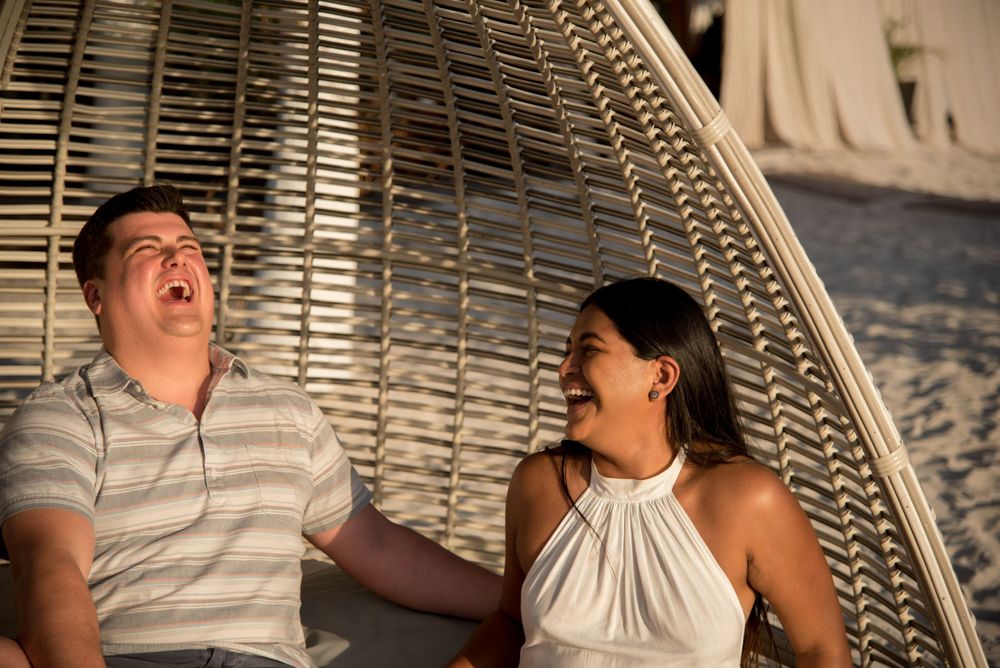 Maureen and John laughing together on a beach-style couch in the beautiful Isla Mujeres