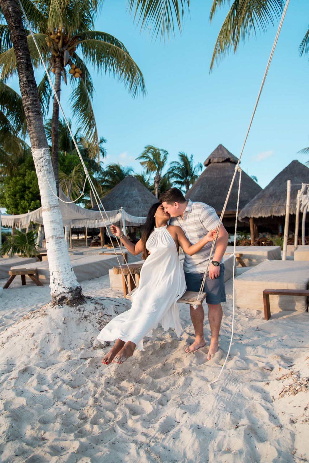A playful shot of the couple on swings, kissing and enjoying each other's company