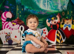 Whimsical Alice in Wonderland themed backdrop with teapots and playing card characters on a checkered floor.