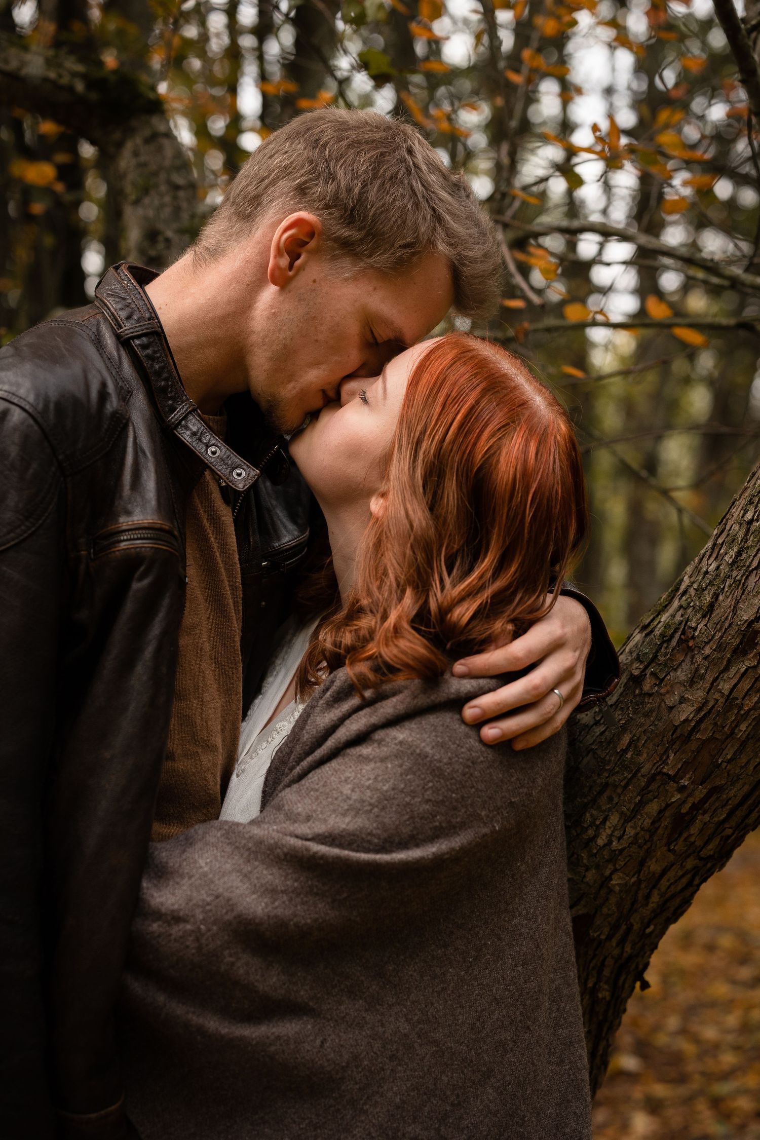 Man and woman kissing in the woods.