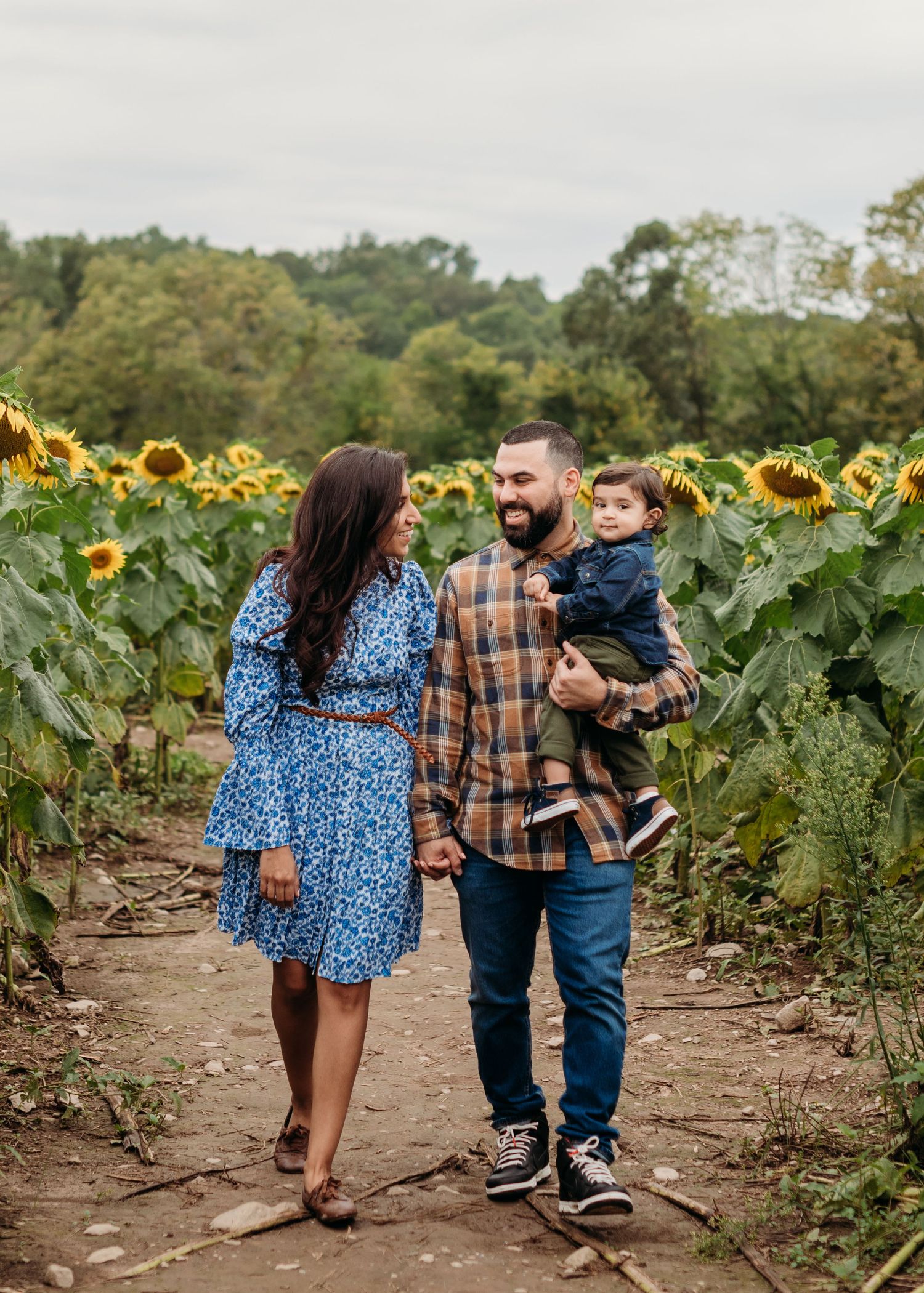 Family walking together through a beautiful sunflower field on a sunny autumn day at Von Thun Farms in Washington, New Jersey.