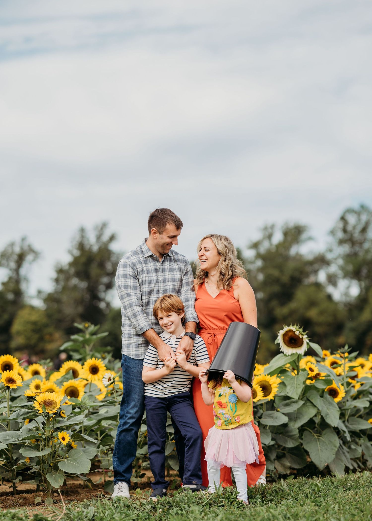 Family enjoying a sunny day together in a beautiful sunflower field, surrounded by bright yellow blooms at Holland Ridge Farms.