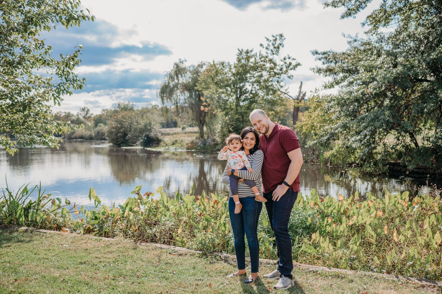 Couple standing together near scenic pond with trees and grassy bank on sunny autumn day in Verona.