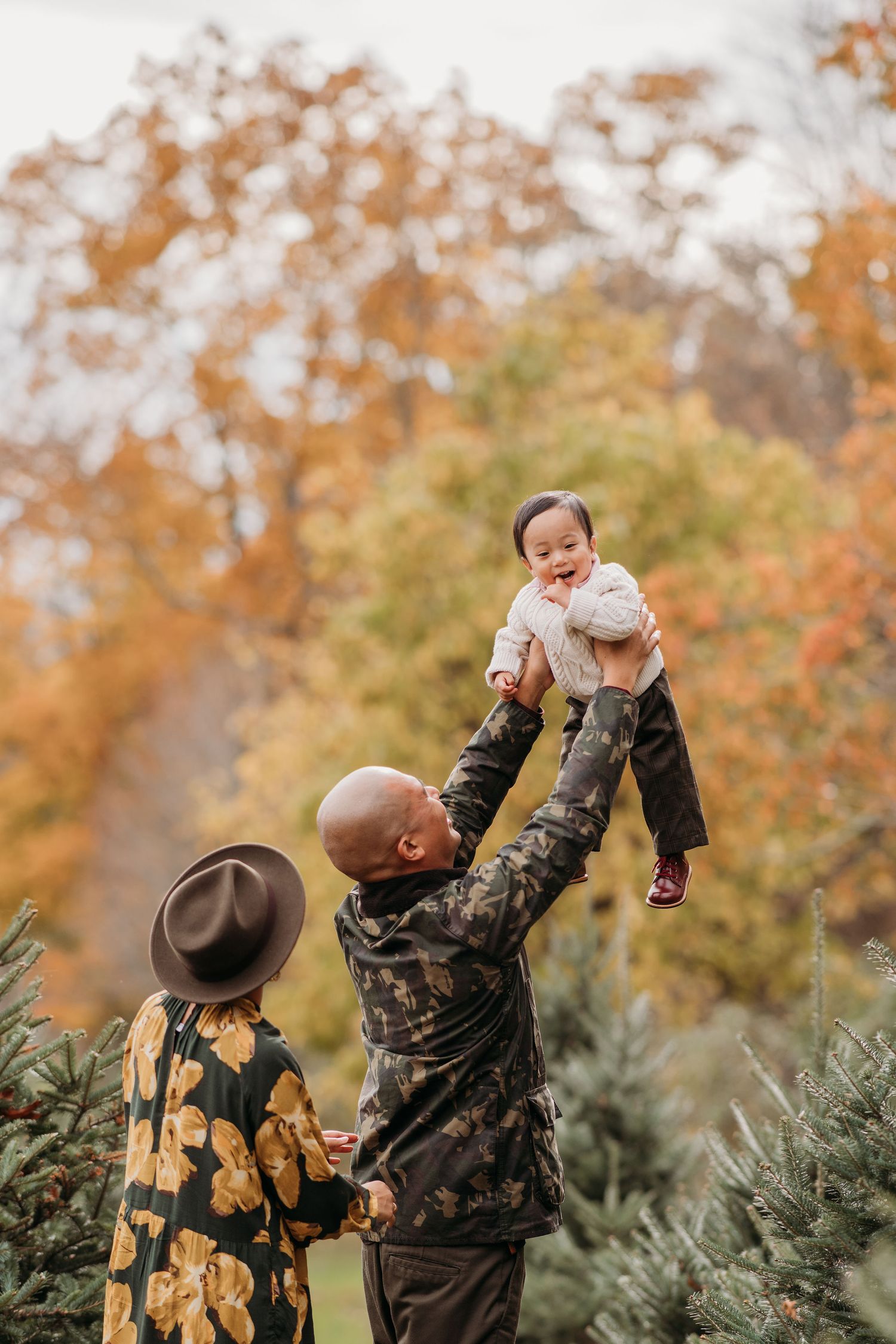 A family enjoying a fall day outdoors together among autumn foliage while wearing camouflage clothing.