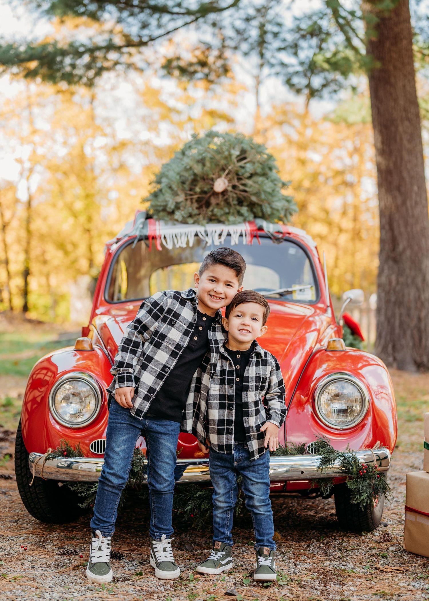 Red vintage Volkswagen Beetle decorated with Christmas wreath parked in autumn forest setting in Montclair.
