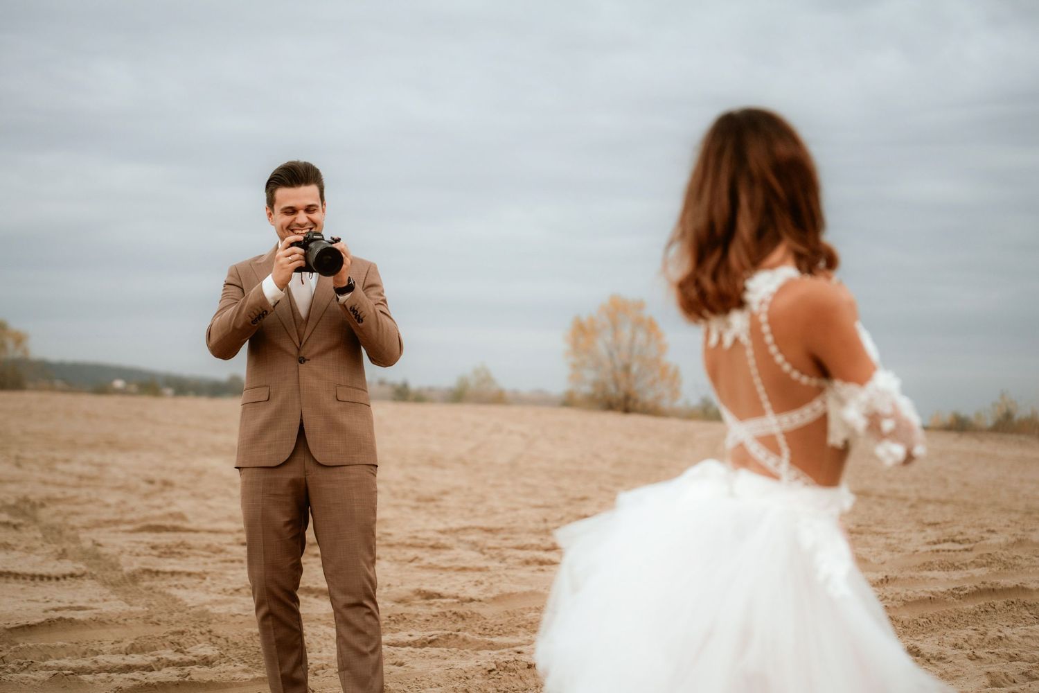 Candid moment of couple taking photos during their desert wedding photoshoot.
