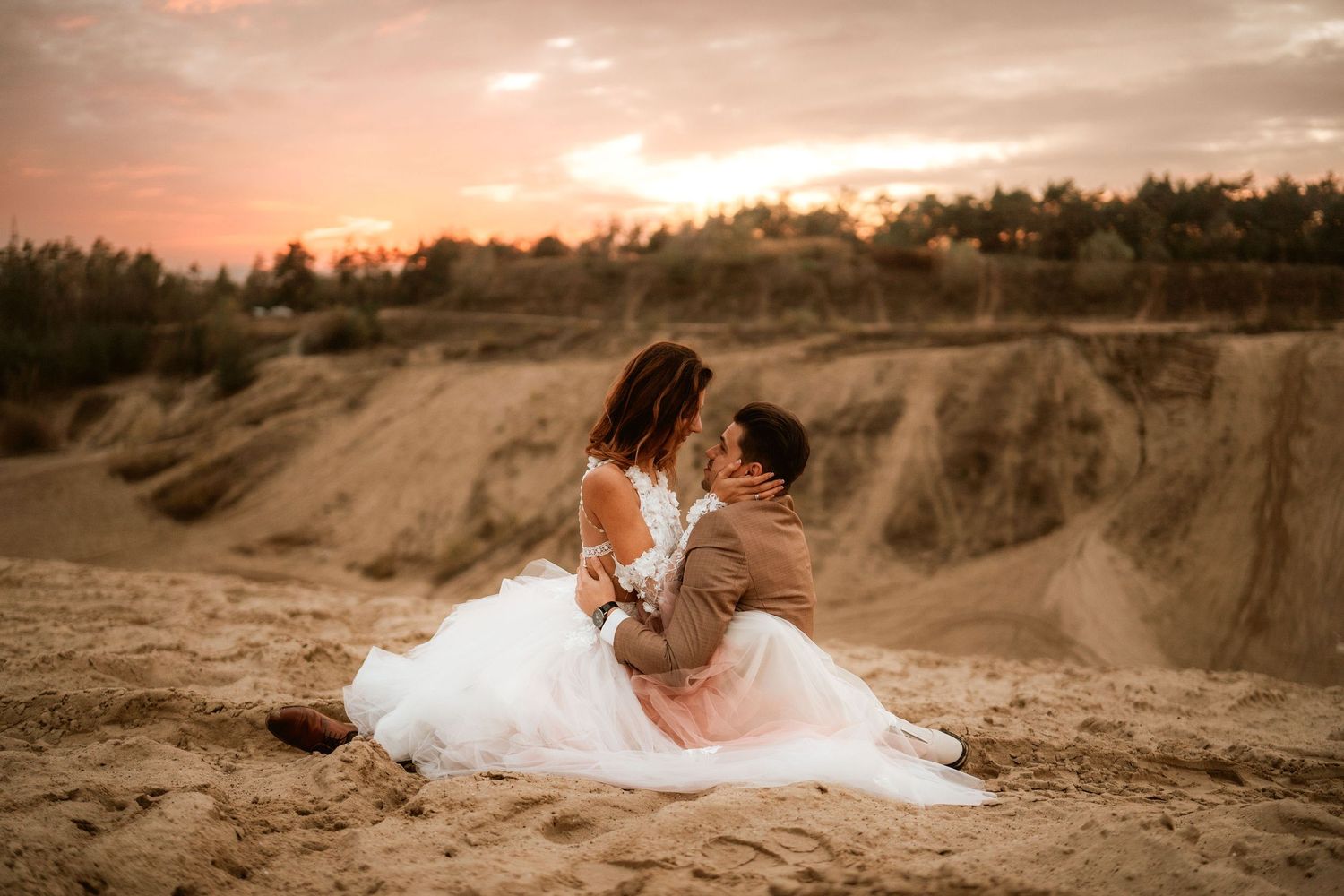 Romantic embrace captured during golden hour in a desert setting.
