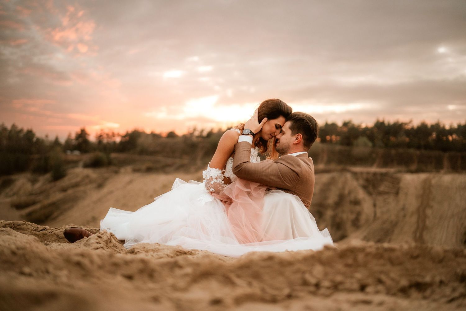 Intimate wedding moment captured during sunset in desert terrain.