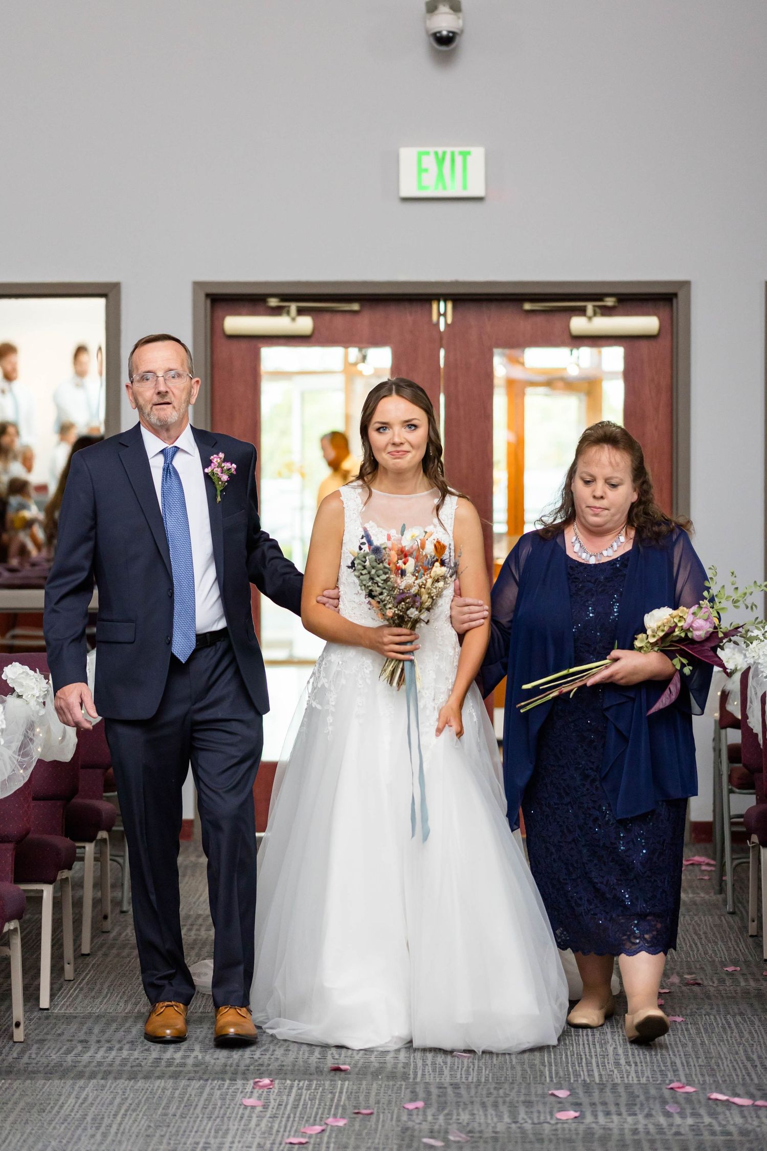 bride walking down the aisle with her mom and dad