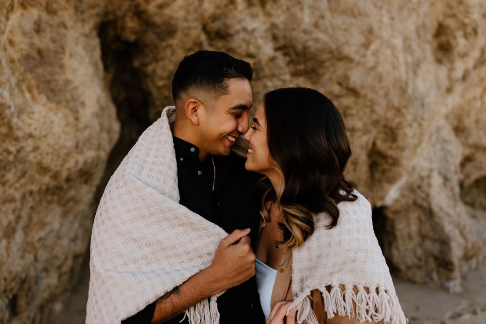 An intimate moment shared between a couple wrapped in a cozy white blanket.