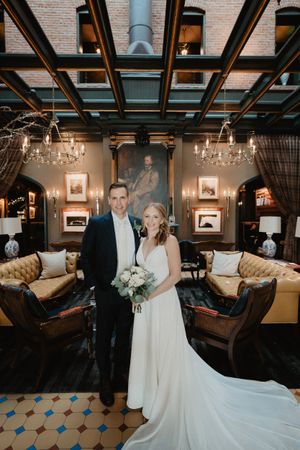 Elegant wedding portrait in luxurious indoor venue with chandeliers and vintage decor.