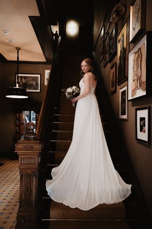 Dramatic bridal portrait on vintage staircase with flowing white gown.
