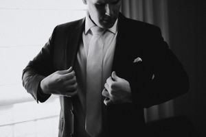 Close-up of formal attire adjustments in black and white photography.