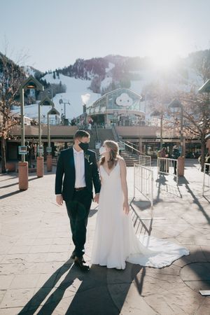 Couple in wedding attire standing at a snowy ski resort base area.