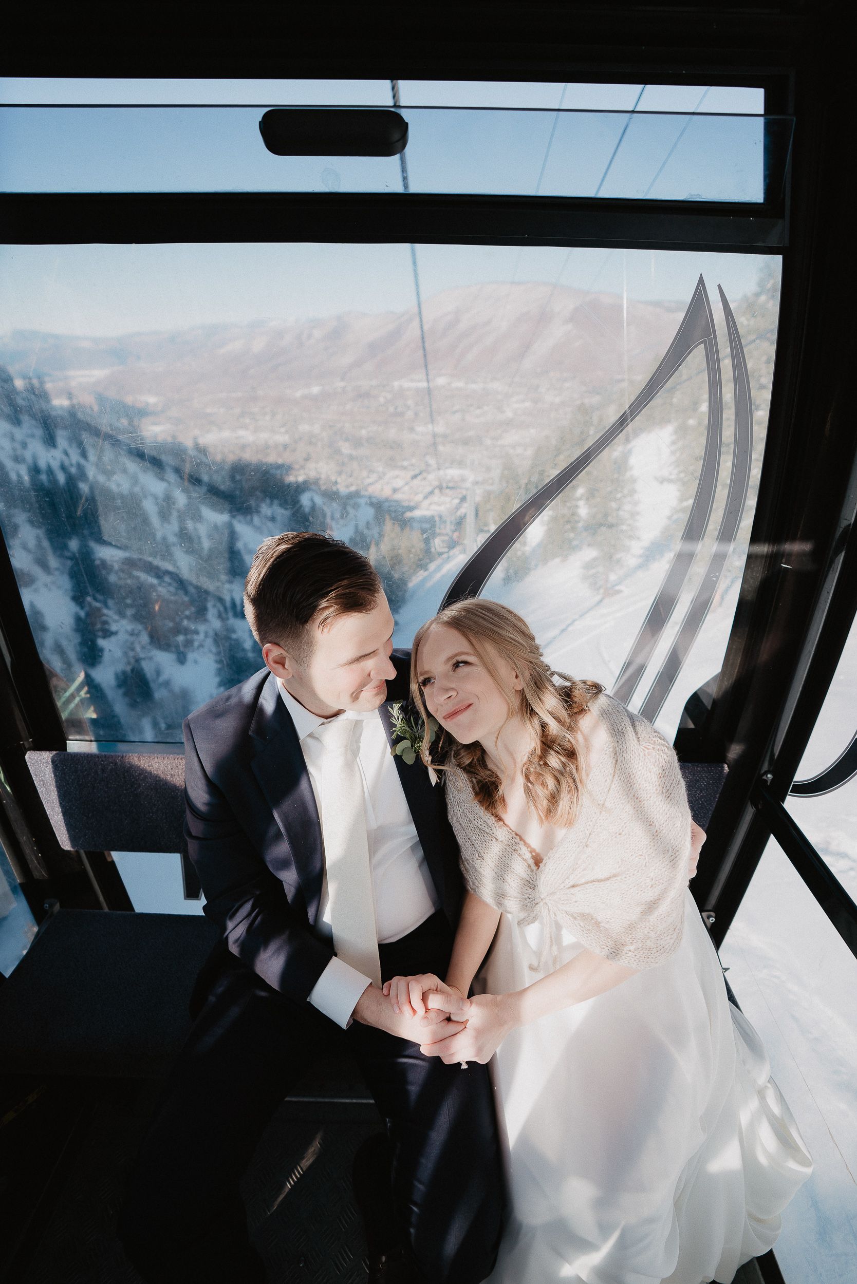 Couple sharing intimate moment inside ski gondola with mountain views.