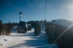 Ski gondolas moving across snowy mountain slopes on a bright winter day.