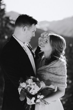 A romantic black and white portrait of a couple sharing an intimate moment with a bouquet of flowers.