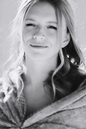 A close-up black and white portrait showing a warm smile wrapped in a cozy shawl.