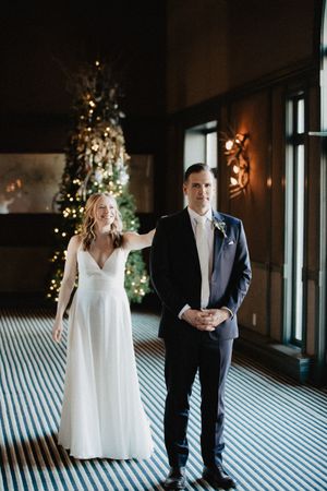 Wedding couple standing in an elegant room with a Christmas tree in the background.