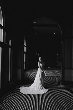 Dramatic black and white bridal portrait in a dark hallway with flowing wedding dress.