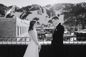 Black and white photo of wedding couple on balcony with mountain landscape backdrop.