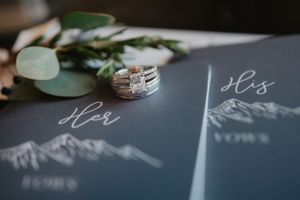 Wedding rings displayed with eucalyptus leaves on mountain-themed stationery cards.