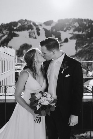 Black and white wedding portrait showing tender moment against mountain backdrop.