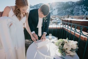 Couple signing marriage certificate on outdoor terrace with floral arrangements.