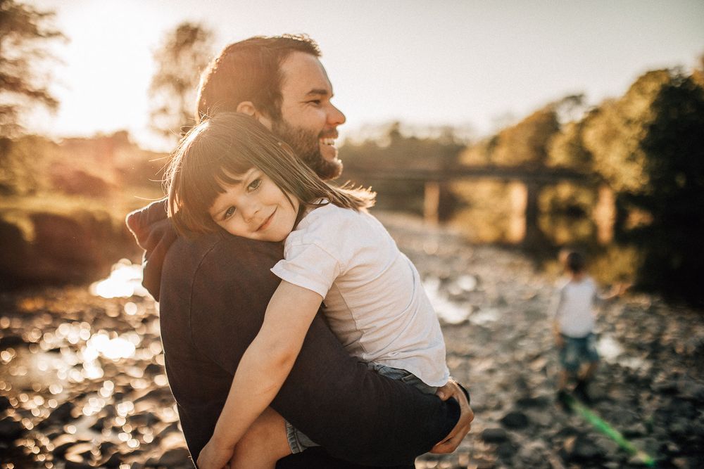 golden light a man is lifting and hugging a little boy, both are smiling