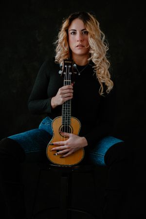Sandra on a black backdrop with her ukulele