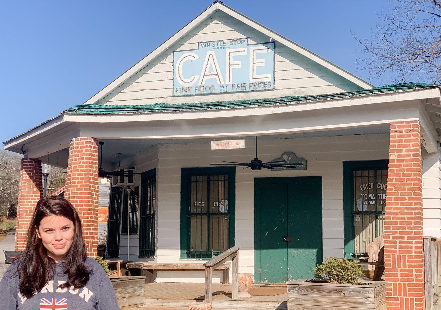 Historic cafe building with brick columns and green trim in small town setting.