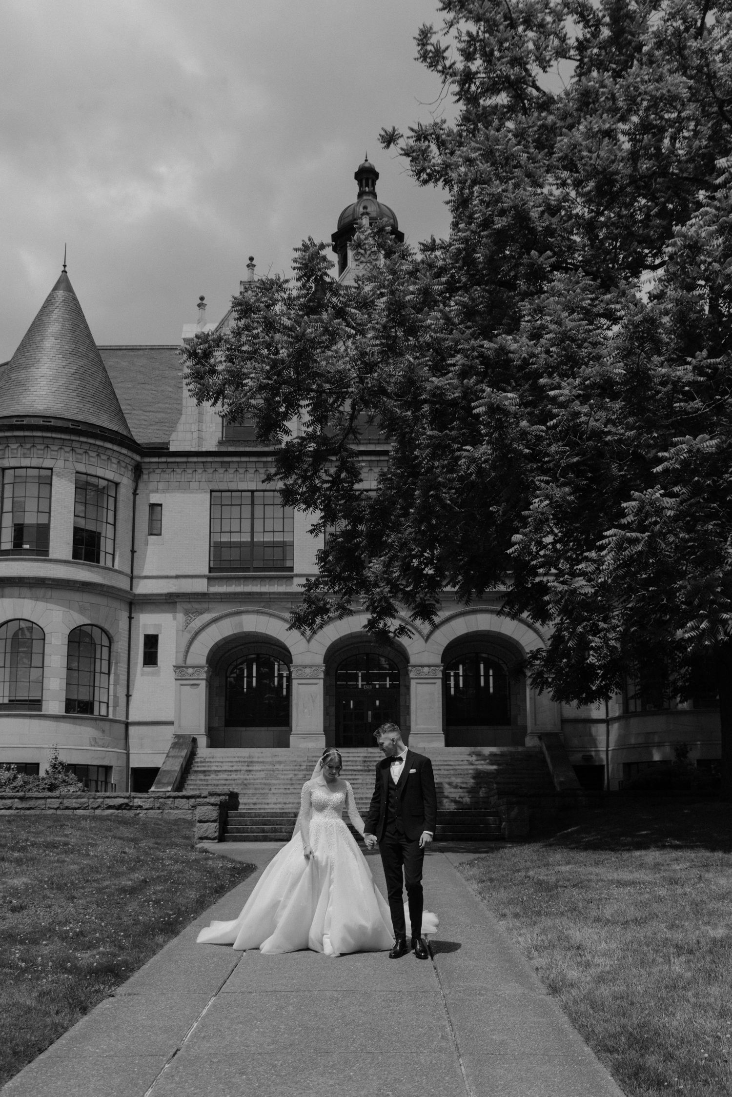 Classic black and white wedding portrait in front of historic mansion with arched doorways.