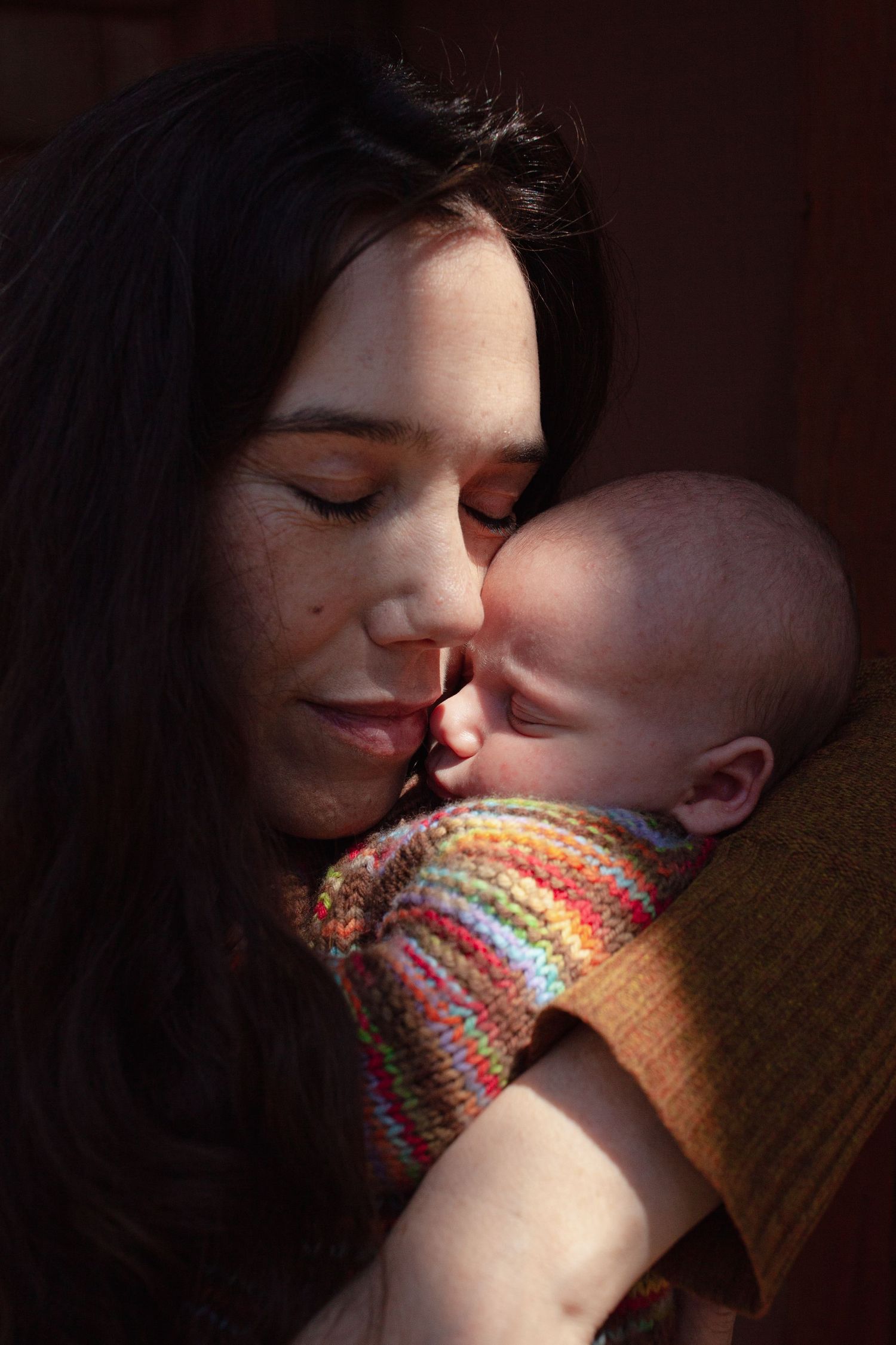 Tender moment between parent and infant in warm lighting.