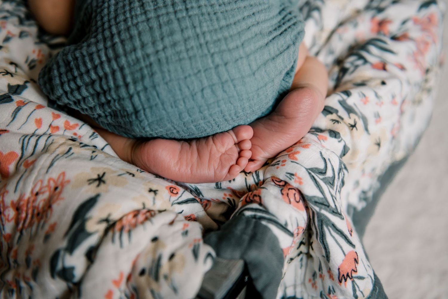 Close-up of tiny baby feet resting on floral patterned fabric.