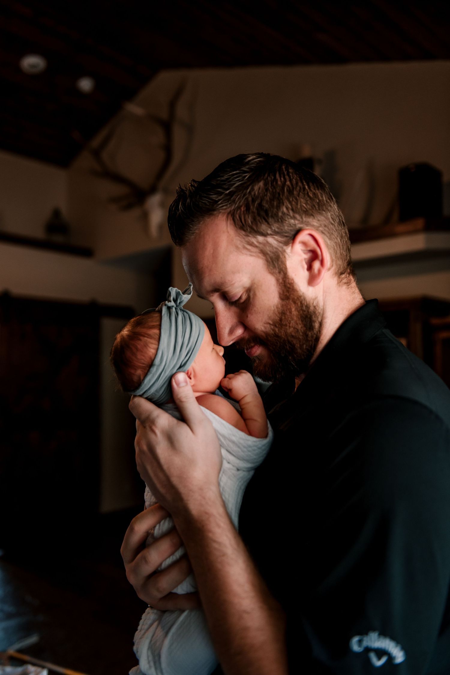 Intimate moment between parent and newborn baby in soft lighting.