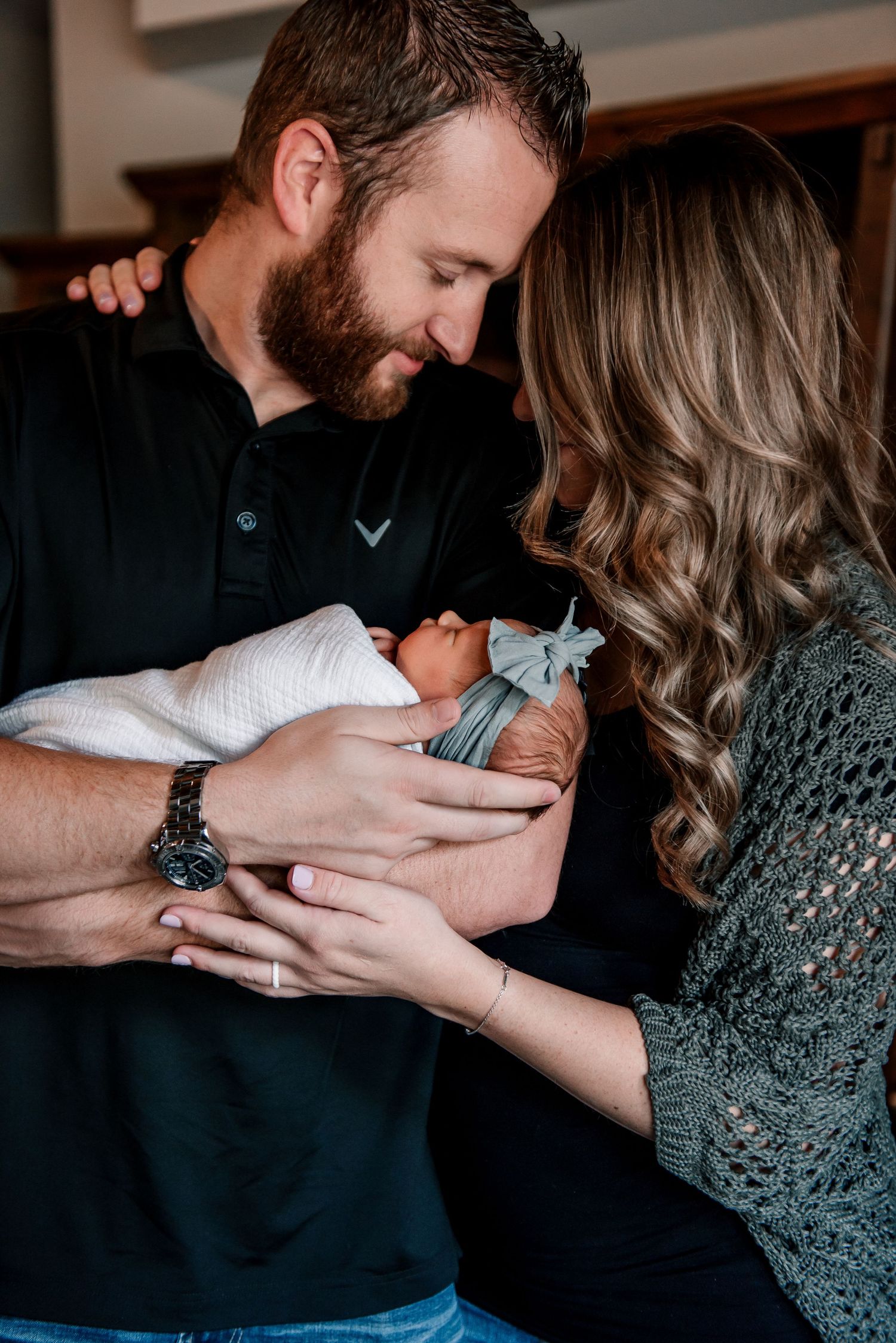 Parents sharing tender moment while holding their newborn baby.