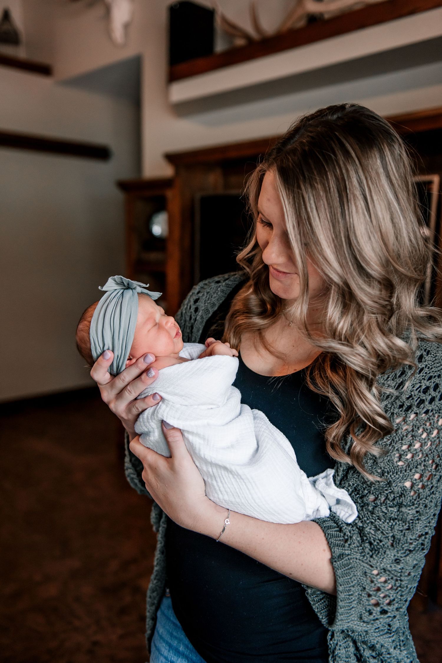 A tender moment as a parent cradles a newborn baby wrapped in white against a dark background.