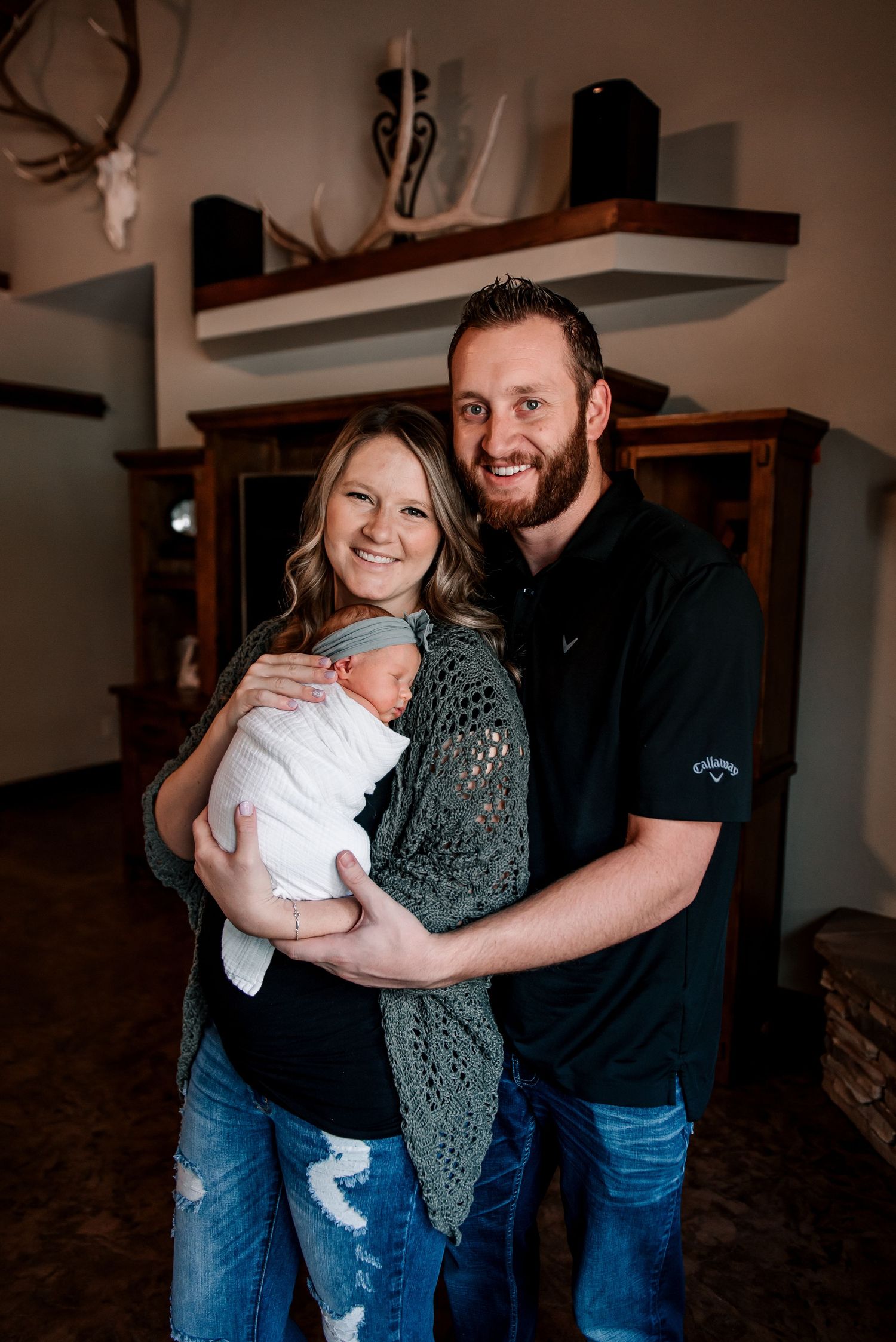 Family members share joyful moments while holding a newborn baby in a cozy home setting.
