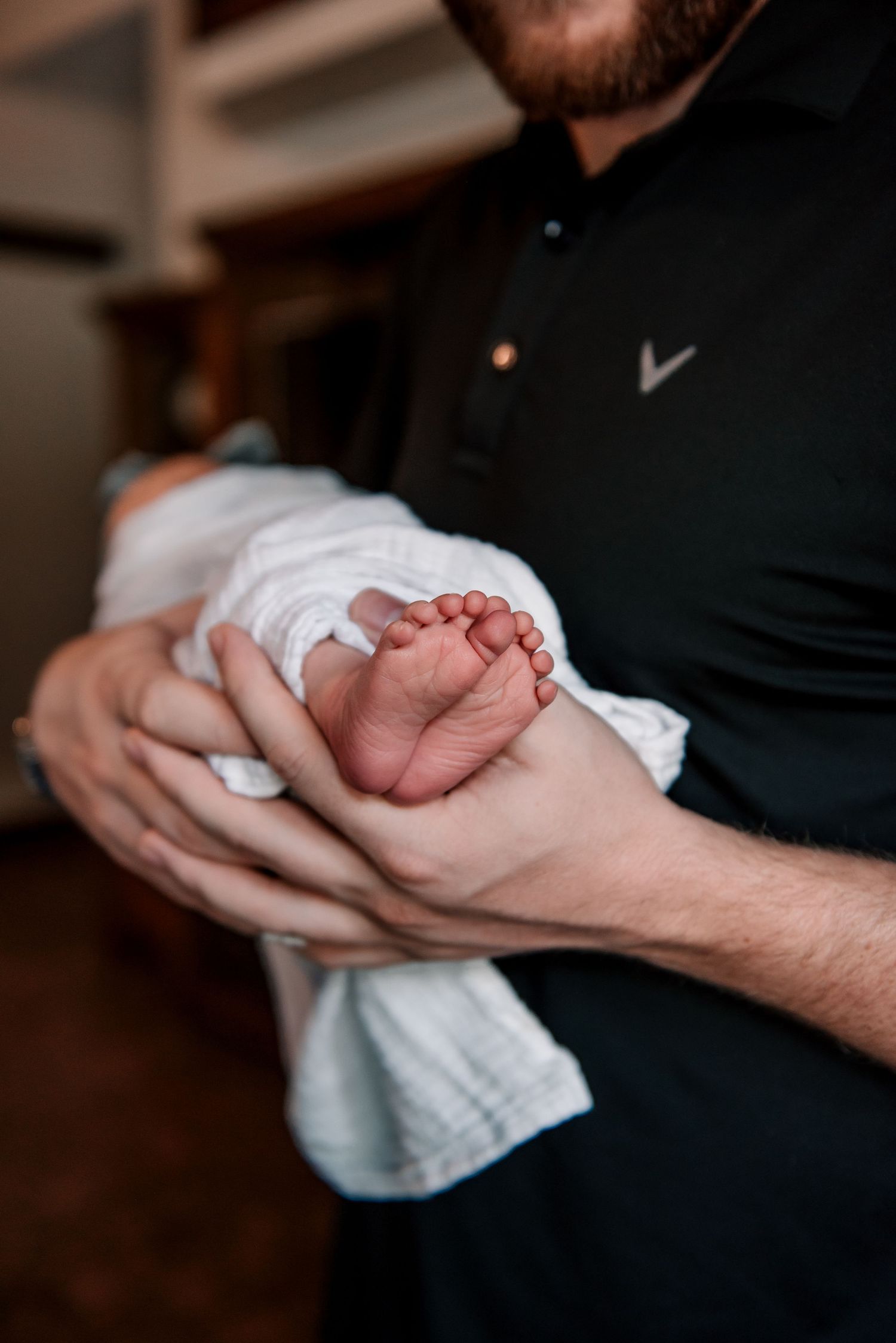 Close-up shot of tiny newborn feet being gently held in adult hands.